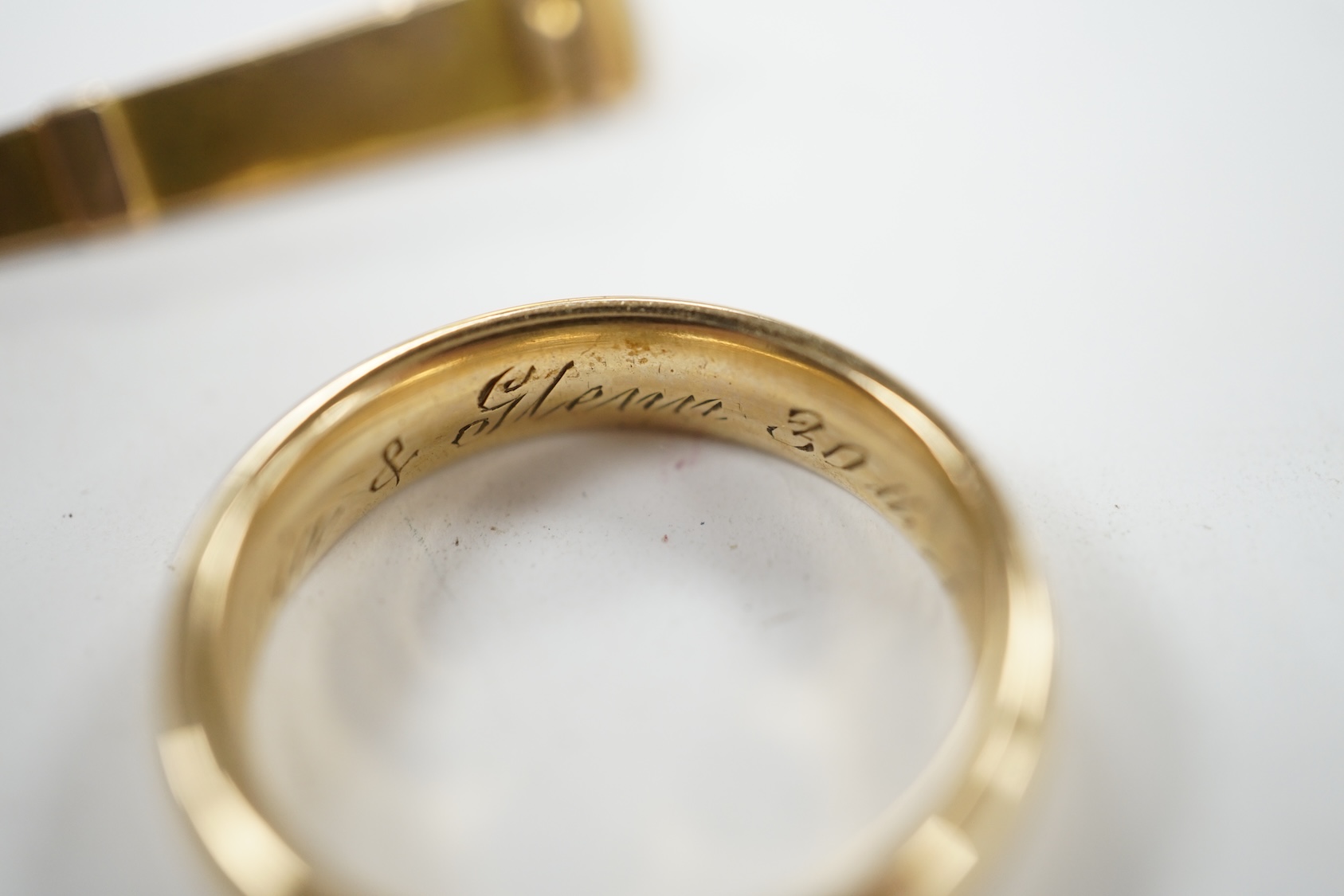 A 9ct gold wedding band, with engraved inscription, size Q and a yellow metal needle? case, 8.4 grams. Condition - fair